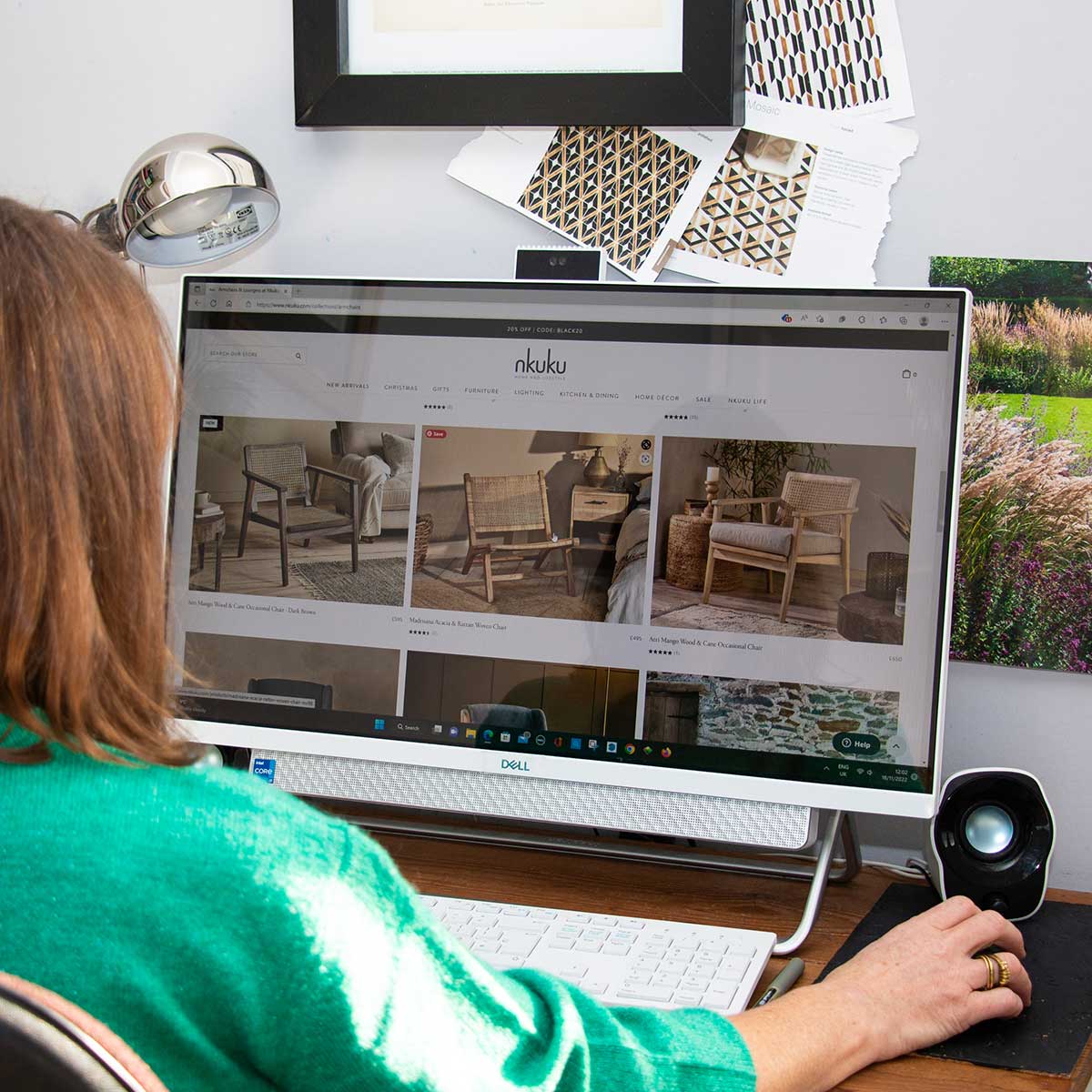 Female interior designer sat at her computer researching into furniture options for her client.